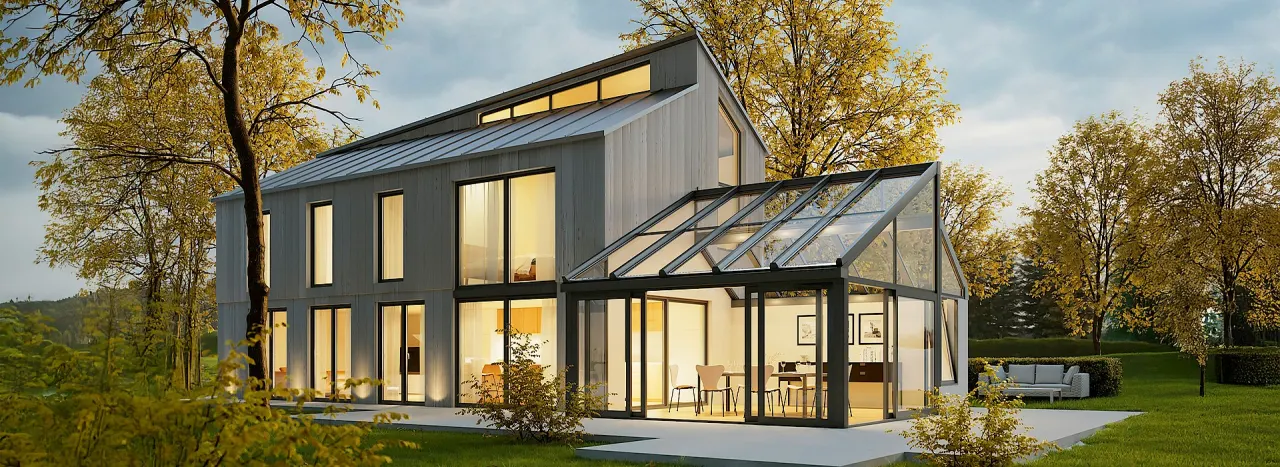 Moderner Wintergarten aus Glas und Aluminium an einem Wohnhaus in der Abenddämmerung